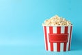 Striped bucket with popcorn on blue background Royalty Free Stock Photo