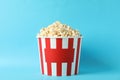 Striped bucket with popcorn on blue background Royalty Free Stock Photo