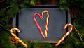 Striped candy canes forming heart on baking tray, happy Christmas celebration