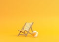 Striped deck chair and beach ball on a yellow background