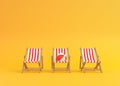 Striped deck chairs and beach ball on a yellow background