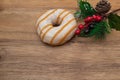 Striped Donut in glaze and festive pine branch on wooden natural background