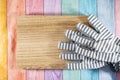 Striped gardening gloves on a wood plank, over a pastel wooden rainbow background. Useful for spring gardening concepts and Royalty Free Stock Photo