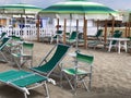 Striped green beach umbrella and sun beds on sandy beach on sunny day. vacation. outdoors furniture Royalty Free Stock Photo