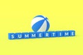 Striped inflatable beach ball and cubes with word summertime on blue background. Recreation on sea or pool in summer Royalty Free Stock Photo