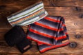 Striped knit striped scarves and black knitted sleeves on wooden background