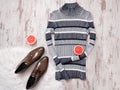 Striped knitted sweater, brown patent leather shoes, halves of cut grapefruit. Wooden background.