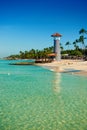 Striped lighthouse on sandy shore with palm trees. Royalty Free Stock Photo