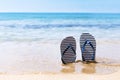 Striped marine flip flops on a sandy beach Royalty Free Stock Photo