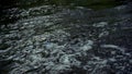 Striped paper boat floats in dirty water of river in slow motion.