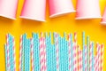 Striped pink and white blue polka dot paper drinking straws pink cups on bright yellow background. Kids birthday party celebration Royalty Free Stock Photo