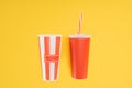 Striped popcorn bucket and red disposable cup with straw isolated