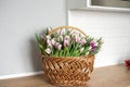 Striped purple tulips of the flaming flag variety stand on a table in a basket in the kitchen