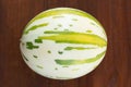 A striped round melon is a wooden table. Royalty Free Stock Photo