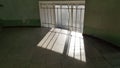 Striped shadows on floor from metal lattice window