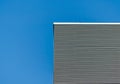 Striped wall of a gray tall building against a blue clear sky