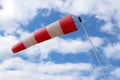 Striped windsock at airport on the background of beautiful clouds