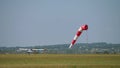 Striped windsock swings in wind on blue sky background