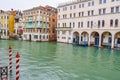 Striped and wooden mooring poles and colorful Venetian gothic architecture buildings in Venice, Italy