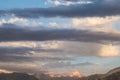 Stripes of storm clouds against the background of cumulus orange above the peaks of the mountains in the distance. Royalty Free Stock Photo