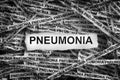 Strips of newspaper with the word Pneumonia typed on them. Black and White