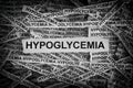 Strips of newspaper with the words Hypoglycemia typed on them. Black and white