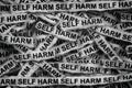 Strips of newspaper with the words Self Harm typed on them. Black and white. Royalty Free Stock Photo