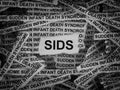 Strips of newspaper with the words SIDS (Sudden Infant Death Syndrome) typed on them. Black and white