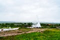 Strokkur geyser and tourist visitors in Haukadalur valley geothermal area in southwestern Iceland