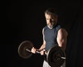 Strong, active, middle aged man with gray beard lifting heavy weights in studio setting, 2 thirds profile view