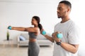 Strong African American couple exercising with dumbbells at home during covid isolation, selective focus Royalty Free Stock Photo