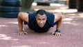 Strong African Anerican sportsman doing push up exercises after jogging at park in morning