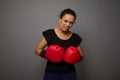 Strong African woman poses against gray wall background with red boxing gloves. Concept of Black Friday and boxing Day, Blow to Royalty Free Stock Photo