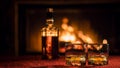 Strong alcohol in a bottle and two glasses on the table. In the background a fire burns in the fireplace Royalty Free Stock Photo