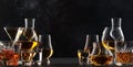 Strong alcoholic drinks, spirits and distillates iset in glasses: cognac, scotch, whiskey and other. Black bar counter background