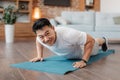 Strong asian mature man making strength workout, standing in plank pose or doing push ups at home on yoga mat Royalty Free Stock Photo