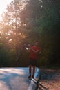 Strong athlete cyclist biker carrying his bicycle on his back on an asphalt road through deep green woods at sunset. Flat tire