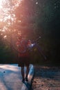 Strong athlete cyclist biker carrying his bicycle on his back on an asphalt road through deep green woods at sunset. Flat tire