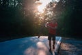 Strong athlete cyclist biker carrying his bicycle on his back on an asphalt road through deep green woods at sunset. Flat tire