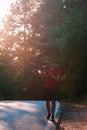 Strong athlete cyclist biker carrying his bicycle on his back on an asphalt road through deep green woods at sunset. Flat tire