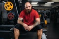 Strong athlete sitting on bench, workout in gym