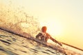Strong athlete splashing in the water at sunset Royalty Free Stock Photo
