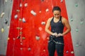 Climber woman puts on belaying harness for practice on artificial rock wall. Royalty Free Stock Photo