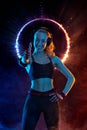 Strong athletic fit woman on black with neon lights background wearing in the sportswear. Fitness and sport motivation. Royalty Free Stock Photo