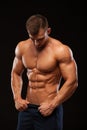 Strong Athletic Man - Fitness Model showing Torso with six pack abs. stands straight and puts his hands in trousers