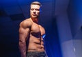 Strong athletic man fitness model torso showing six pack abs.  on dark background with blue filter. Closeup. Royalty Free Stock Photo