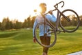 Strong athletic man in sportswear carrying his bicycle and watching amazing sunset after cycling in park Royalty Free Stock Photo