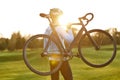 Strong athletic man in sportswear holding a bicycle while standing in park at sunset, cycling outdoors and enjoying Royalty Free Stock Photo