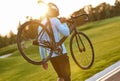 Strong athletic man in sportswear and protective helmet carrying his bicycle after cycling training in park, enjoying Royalty Free Stock Photo