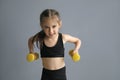 A strong athletic slim fit little girl holds dumbbells in her hands. Royalty Free Stock Photo